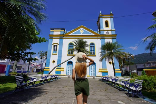 Tourism in Brazil. Back view of young tourist woman in front of the church Igreja Matriz in the historic center of Ubatuba, Brazil.