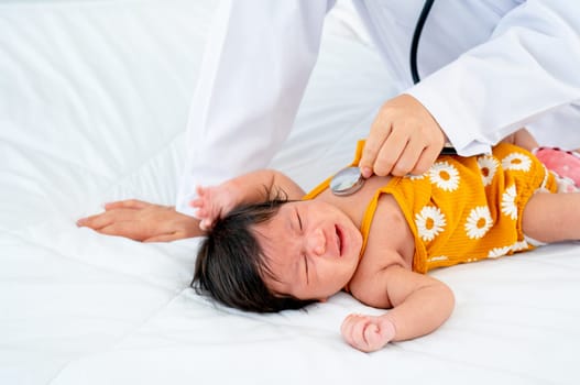 The doctor use stethoscope to check the symptom of newborn baby cry and lie on bed in room with day light.