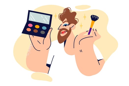Non-binary man does own makeup and holds brush with multi-colored powder and mirror