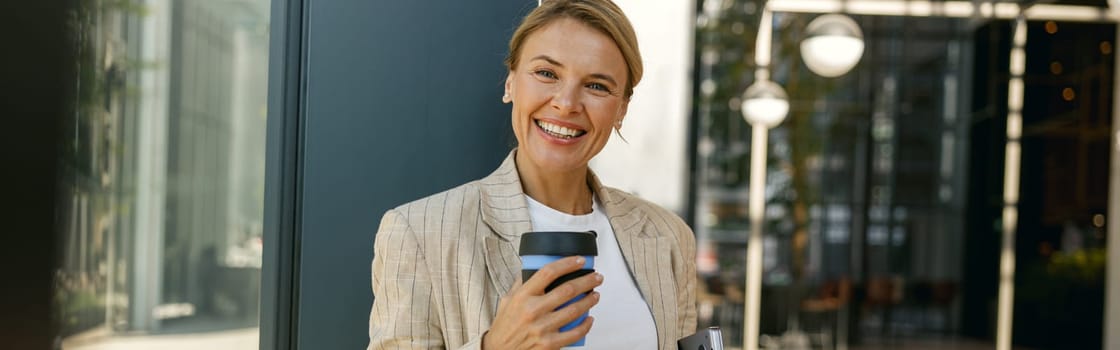 Stylish business woman drinking coffee during break time in modern coworking background