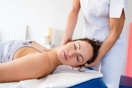 Relaxed woman getting neck treatment in osteopathy clinic