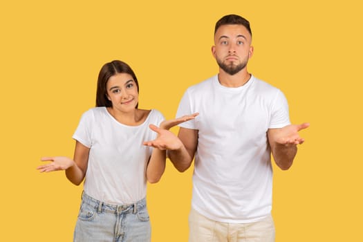 A young couple in white t-shirts shrugging with their palms up