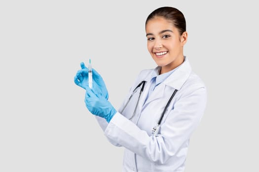 A friendly Caucasian millennial doctor in a lab coat and blue gloves preparing