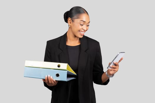 Smiling professional African American businesswoman multitasking with colorful binders