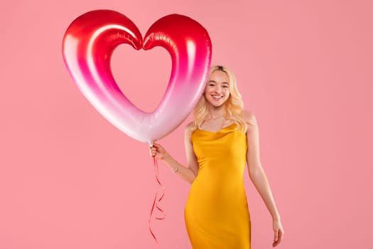 Happy woman with a heart balloon on pink backdrop