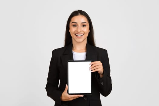 Cheerful businesswoman showcasing blank tablet screen