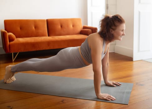 Senior woman standing in plank pose, enjoying her fitness routine at home