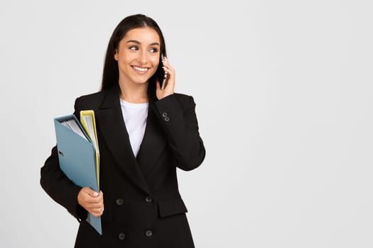 Businesswoman on phone with documents in hand, smiling