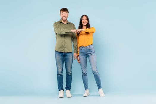 Man and woman fist bumping in casual wear on blue background
