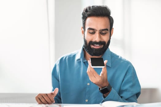 Hindu businessman with beard using voice assistant on phone