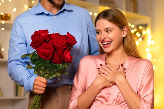 Overjoyed woman receiving red roses from a man, festive backdrop