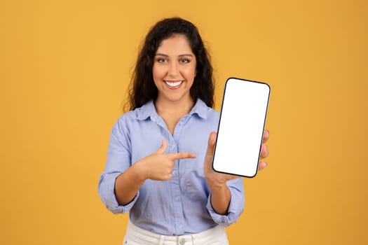 Confident young woman with curly hair presents a smartphone with a blank screen