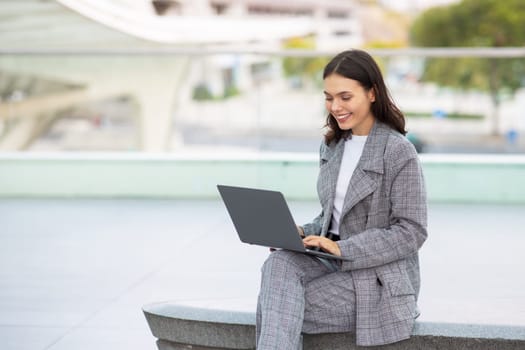 Successful young manager woman programming on laptop outside