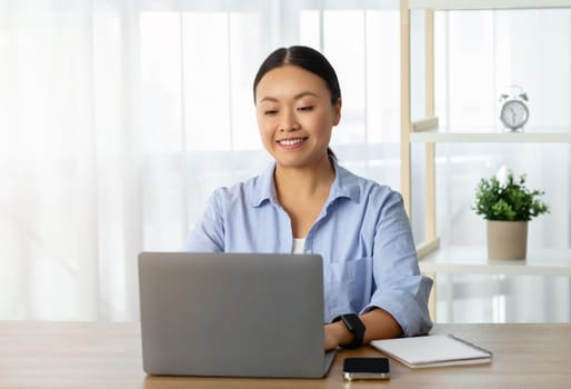 Asian woman freelancer working from home, typing on laptop