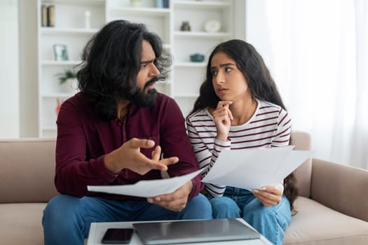 Budget Planning. Stressed Millennial Indian Spouses Holding Papers