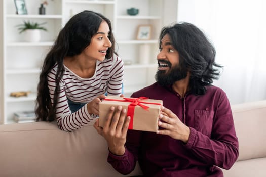 Loving young indian woman giving present her surprised boyfriend