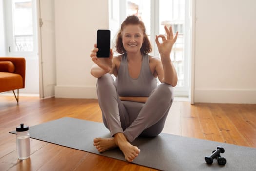 Sporty Senior Woman Holding Blank Smartphone And Showing Ok Gesture