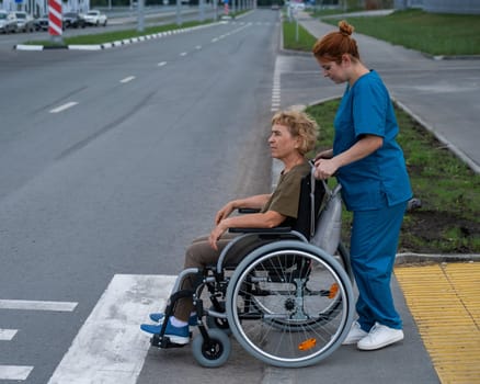 Red-haired nurse pushing an elderly woman in a wheelchair across the road.
