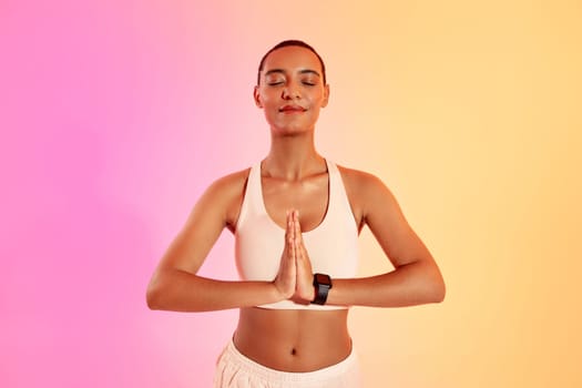 A serene woman with a shaved head is practicing yoga in a peaceful pose, hands in anjali mudra