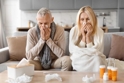 Senior couple sitting on sofa at home with seasonal flu