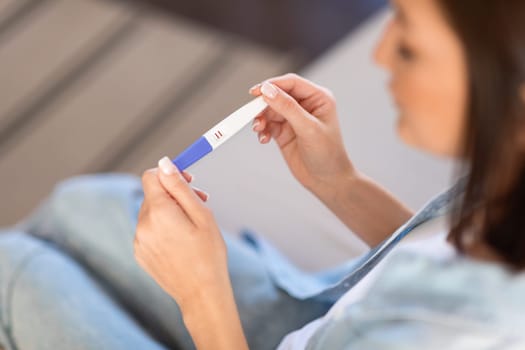 unrecognizable young lady looking at positive pregnancy test at home