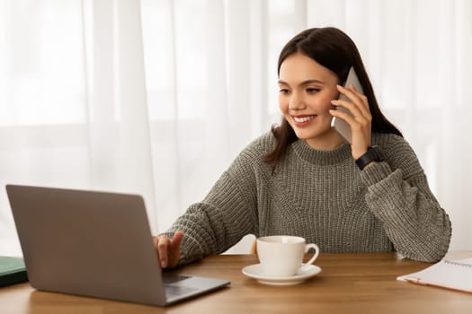 Happy young businesswoman working on laptop, using phone