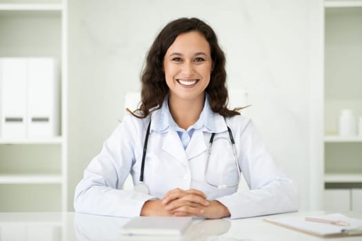 Friendly millennial caucasian woman doctor sitting at desk