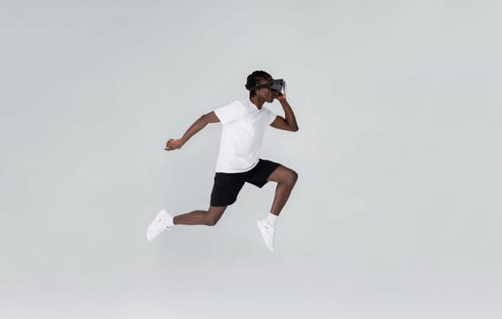 In motion shot of black man wearing vr headset running in studio