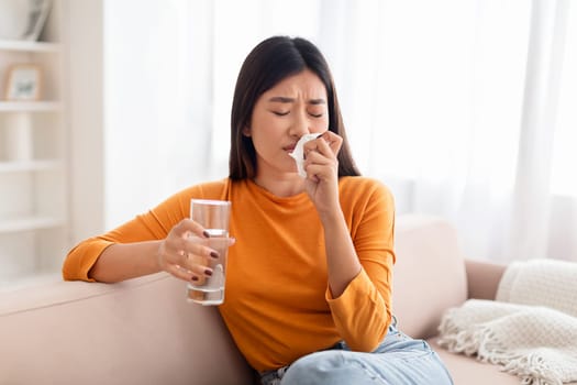 Sick millennial asian woman suffering from nausea at home