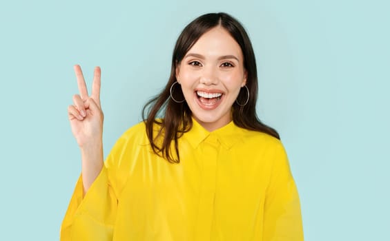 Emotional happy young woman showing peace gesture
