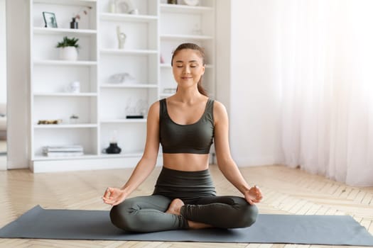Serene young asian woman in sportswear practicing meditation with closed eyes