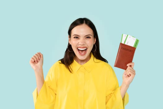 Smiling happy young woman showing passport with air tickets