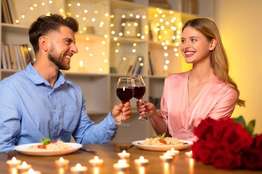 Couple enjoying candlelit dinner with wine and roses