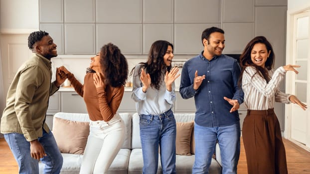 Multiracial group of friends dancing enjoying students party at apartment