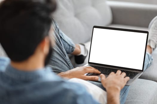 Indian Man Using Laptop Computer With Blank White Screen At Home