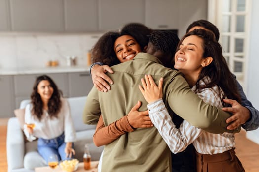 Group of diverse friends sharing hug during home party gathering