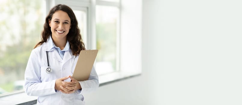 Brunette european woman doctor therapist in white coat holding clipboard