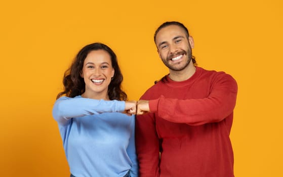 Portrait of positive man and woman doing fist bump