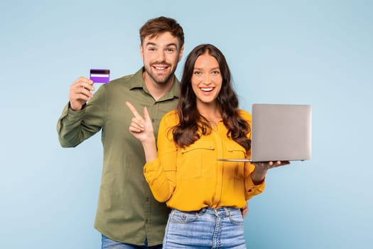 Couple with credit card and laptop on blue background