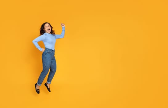 Cheerful carefree young woman jumping on yellow