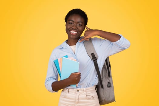Cheerful teen black woman student, with backpack and books, ready to study