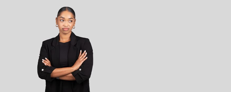 Skeptical African American businesswoman stands with arms crossed