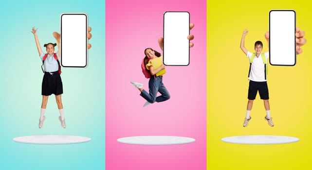Three schoolchildren in uniform joyfully jumping with blank smartphone in hand