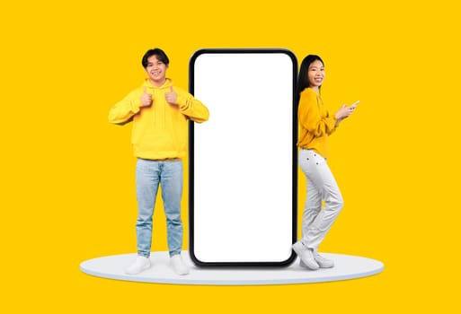 Youngsters in yellow with phones by giant blank screen