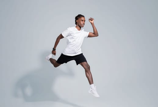 Dynamic black man in sportswear running on grey studio background