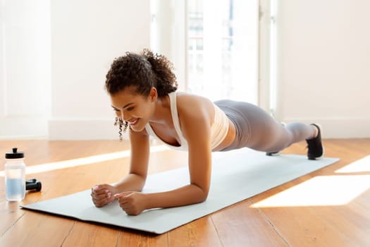 Young fitness woman in sportswear doing elbow plank at home