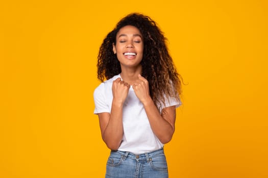 Curly young african american lady gesturing yes in celebration, studio