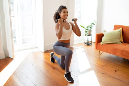 sporty lady doing lunges with dumbbells during domestic workout indoor