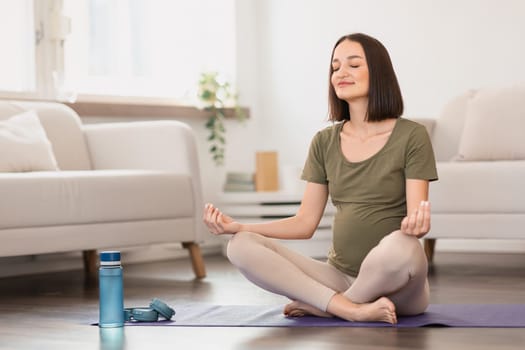 Peaceful expectant woman engages in yoga session sitting meditating indoor