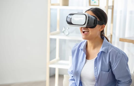 Young asian woman in VR headset touching air at home